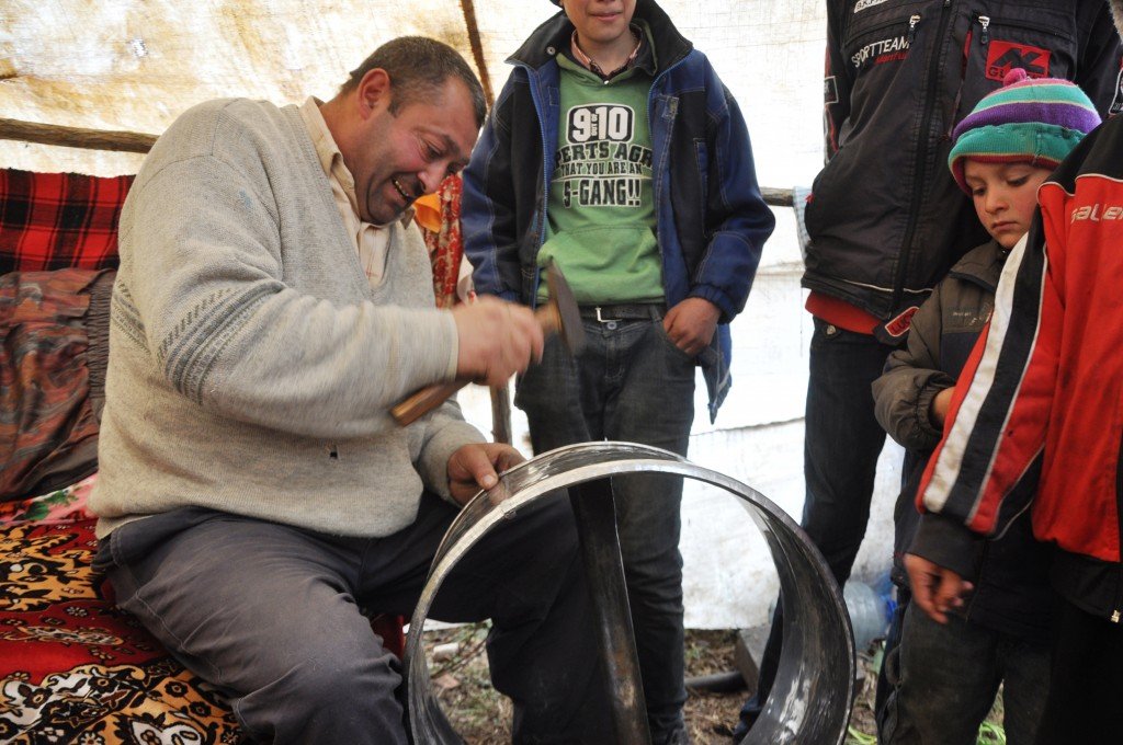 „Capul familiei, un bărbat vânjos, cu mustață, stă pe marginea patului și bate cu ciocanul într-o bucată de tablă de inox.“